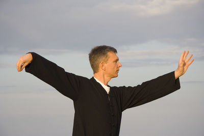 Mid adult man practicing tai chi against sky