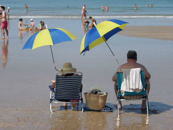 Rear view of people sitting on beach