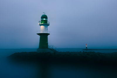 Lighthouse by sea against sky during dawn 