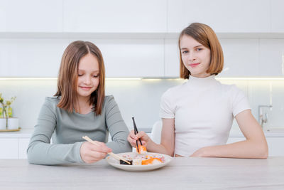 Young woman using mobile phone while sitting at home