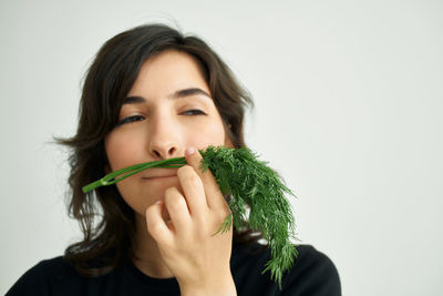 Portrait of young woman holding food against white background