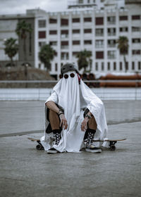 Rear view of skater ghost standing in city in a longboard