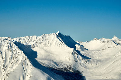 Scenic view of snowcapped mountains against clear blue sky