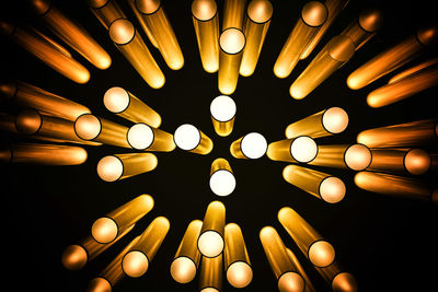 Close-up of illuminated light bulb hanging against black background