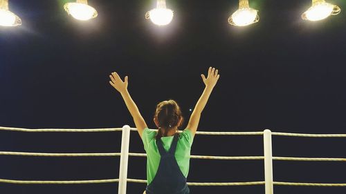Woman standing against illuminated wall at night