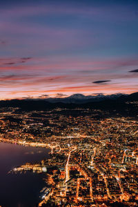 Aerial view of illuminated city against sky at sunset