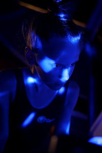 Close-up of a young woman with blue light 