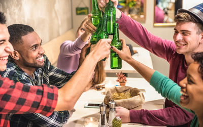 Smiling friends raising toast while sitting in restaurant