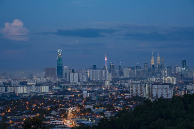 Aerial view of city lit up against cloudy sky