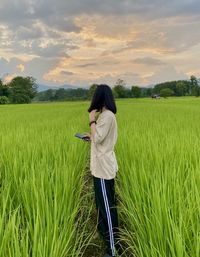 Rear view of woman walking on field against sky