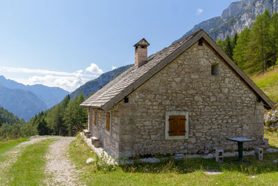 House on field by mountain against sky