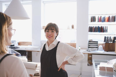 Portrait of smiling female entrepreneur standing with hand on hip in upholstery workshop