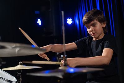 Close-up of boy playing drum at music concert