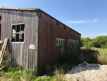 Abandoned cottage on field against sky