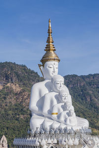 Low angle view of statue against building and mountains against sky