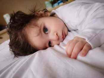 Portrait of cute baby lying on bed at home