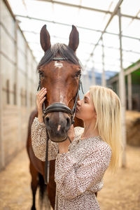 Portrait of woman with horse in stable