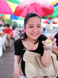 Portrait of smiling young woman holding ice cream at market