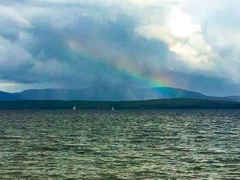 Scenic view of rainbow over sea against sky