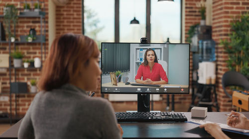 Rear view of businesswoman talking on video call