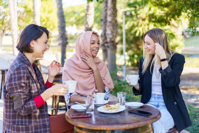 Smiling friends using laptop while sitting in restaurant