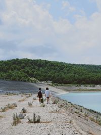 Rear view of women walking on shore against sky