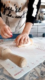 Midsection of woman kneading dough in kitchen