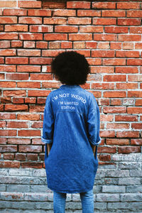 Rear view of boy standing against brick wall