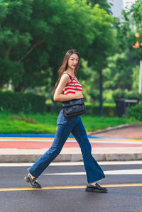 Full length of young woman standing on road