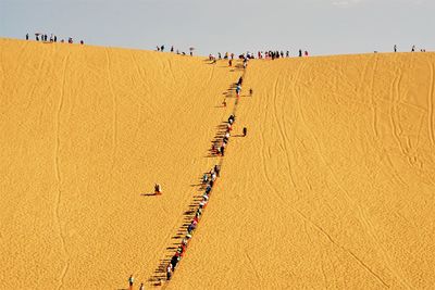 High angle view of people on sand dune against clear sky