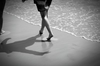 Low section of woman walking on sea shore