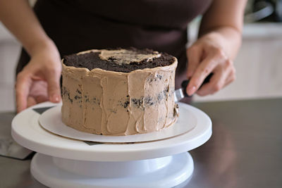 Woman pastry chef making chocolate cake with chocolate cream, close-up. cake making process
