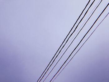 Low angle view of power lines against clear blue sky