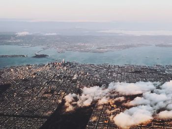 Aerial view of city by sea against sky