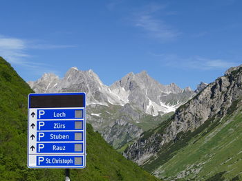 Information sign by mountains against blue sky