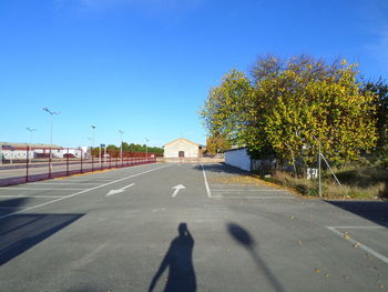 Shadow of man on road against clear blue sky