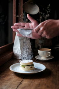 Cropped image of hand holding coffee cup on table