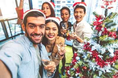 Portrait of cheerful friends toasting drinks during christmas