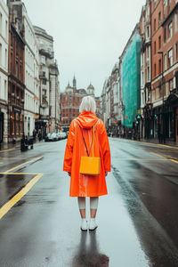 Rear view of woman walking on road in city