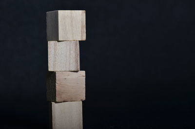 Close-up of wooden blocks stacked against black background