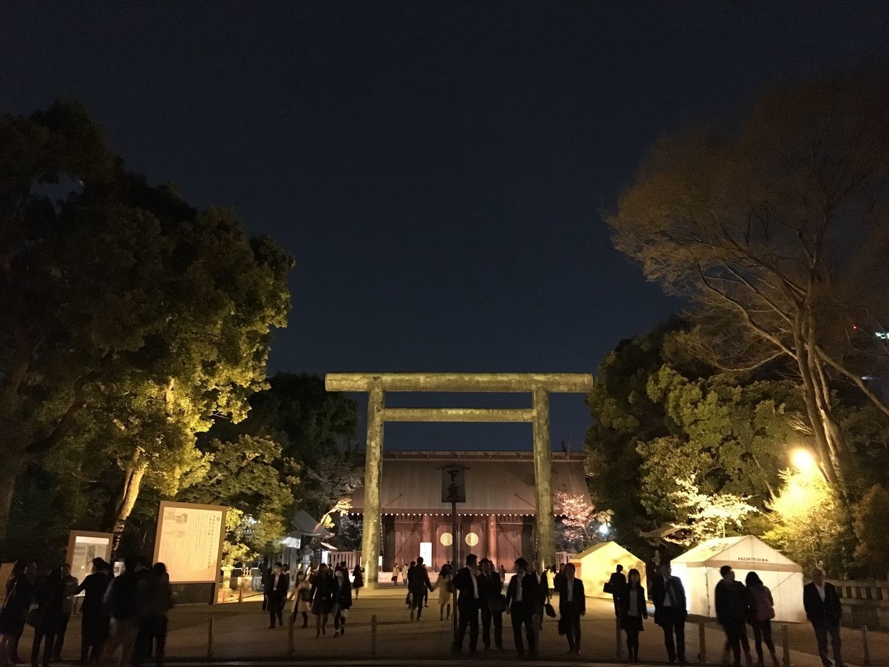 architecture, built structure, building exterior, tree, illuminated, night, large group of people, clear sky, sky, low angle view, people, copy space, outdoors, city, dusk, lifestyles, travel destinations, silhouette