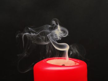 Close-up of burning candle against black background