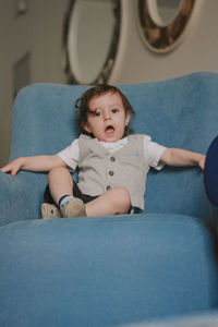 2 years toddler sitting on the chair with an open mouth at home 