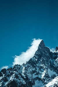 Low angle view of snowcapped mountains against blue sky