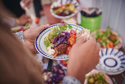 Cropped hands of woman holding meal in plate during social gathering on terrace