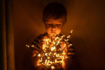 Full length of boy with illuminated lights at home