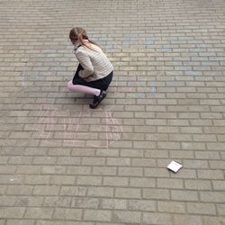 High angle view of girl drawing with chalk on footpath