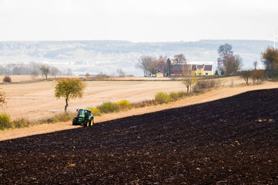 Tractor on field at farm against sky