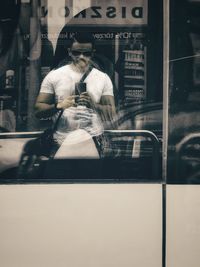 Rear view of man walking on city street seen through window