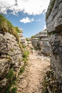 Footpath amidst rocks against sky